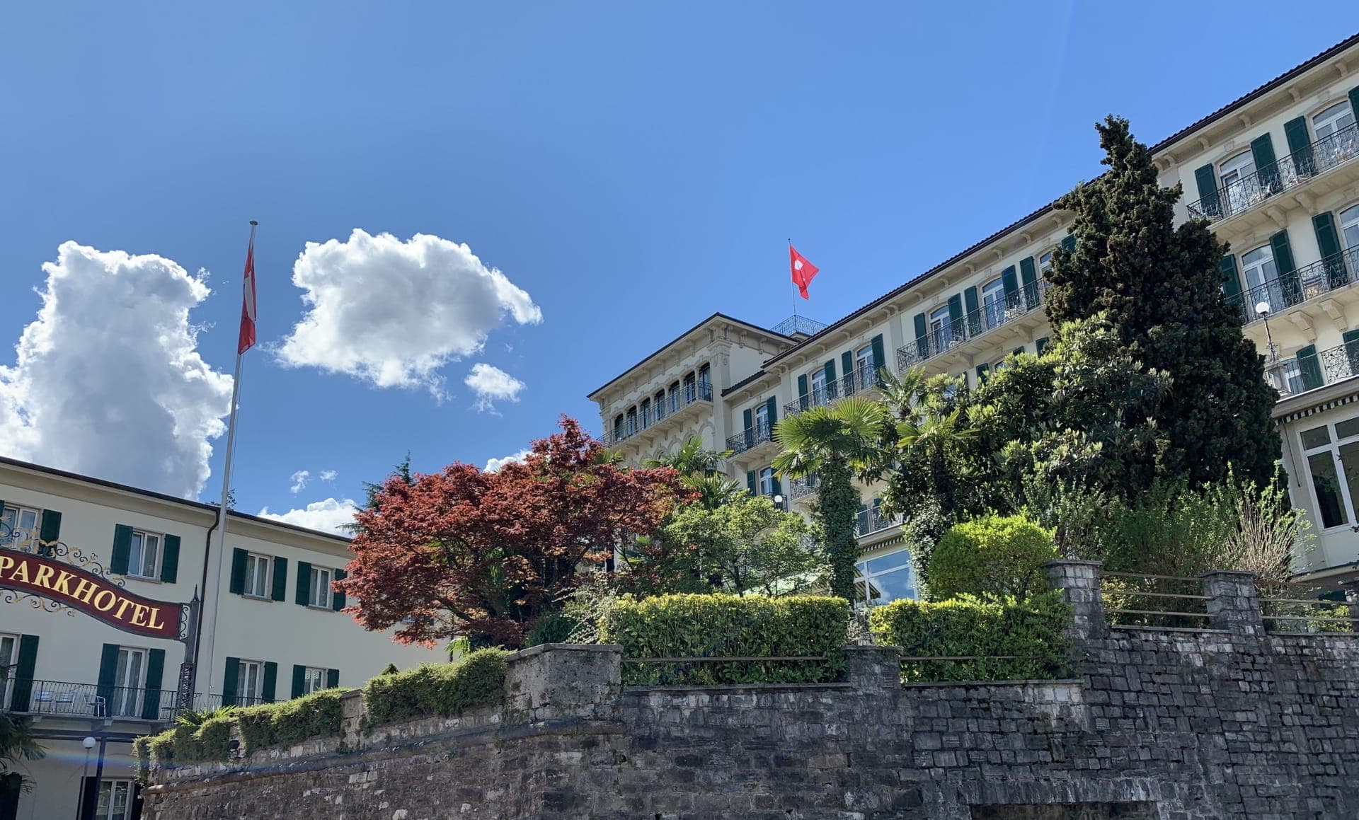 Facciata storica del Continental Parkhotel di Lugano sopra un muro del giardino.