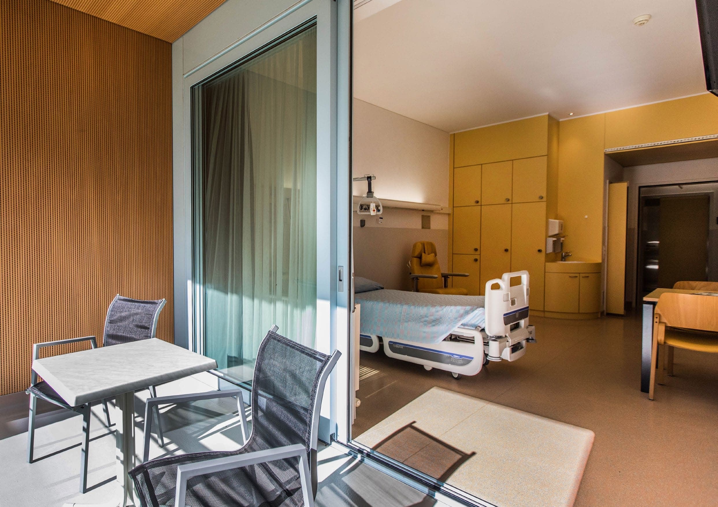 Camera di degenza della Clinica di Riabilitazione EOC di Faido con letto di cura e terrazza antistante.
