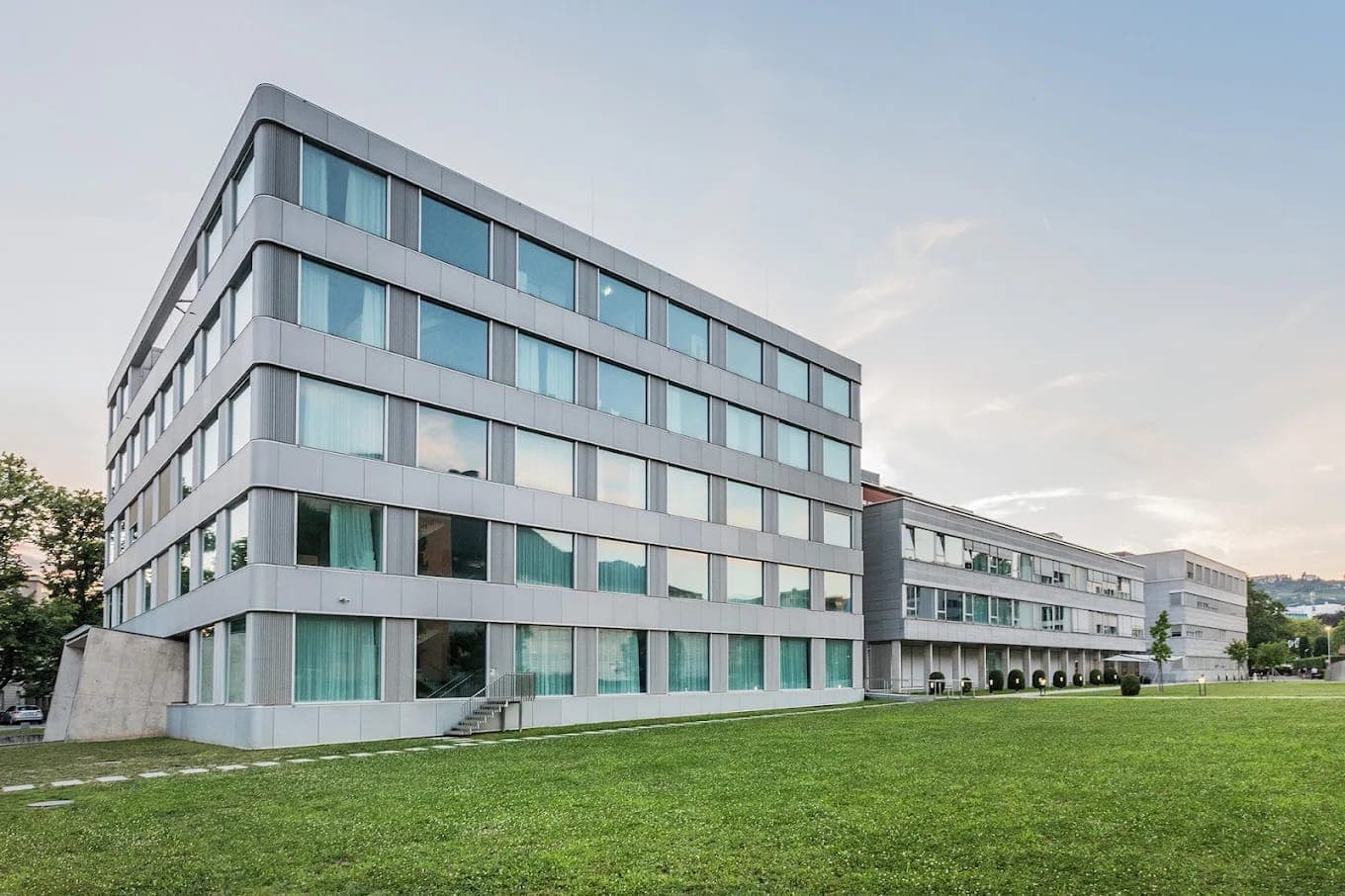 Facciata in vetro dell’Ospedale Italiano a Viganello con prato antistante.
