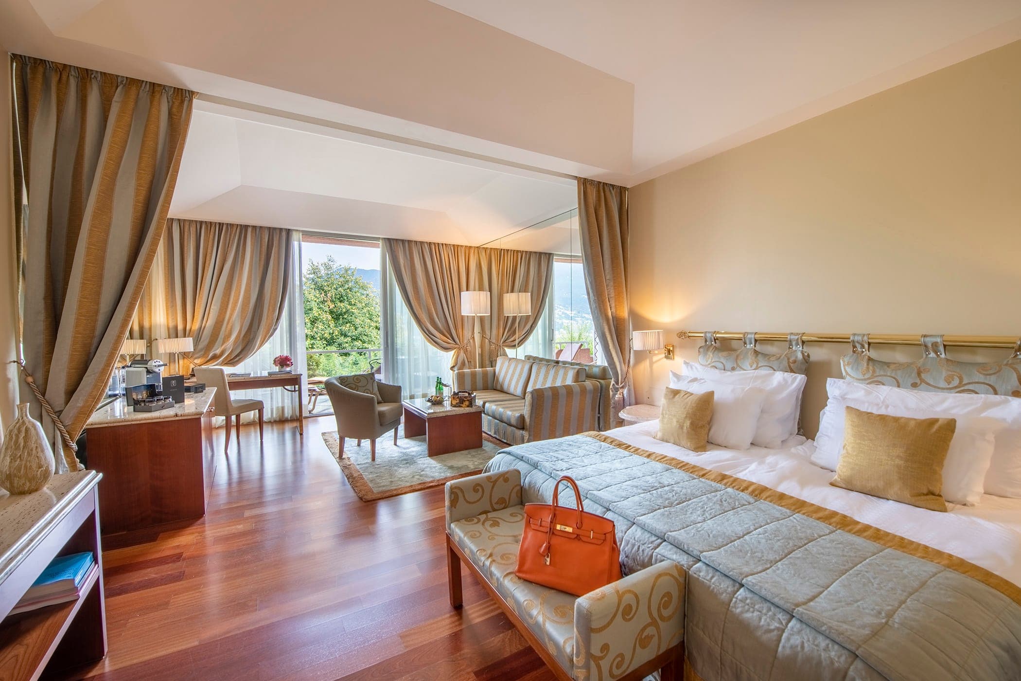 Suite dell’Hotel Principe Leopoldo a Lugano con parquet, letto matrimoniale e salottino alla finestra.