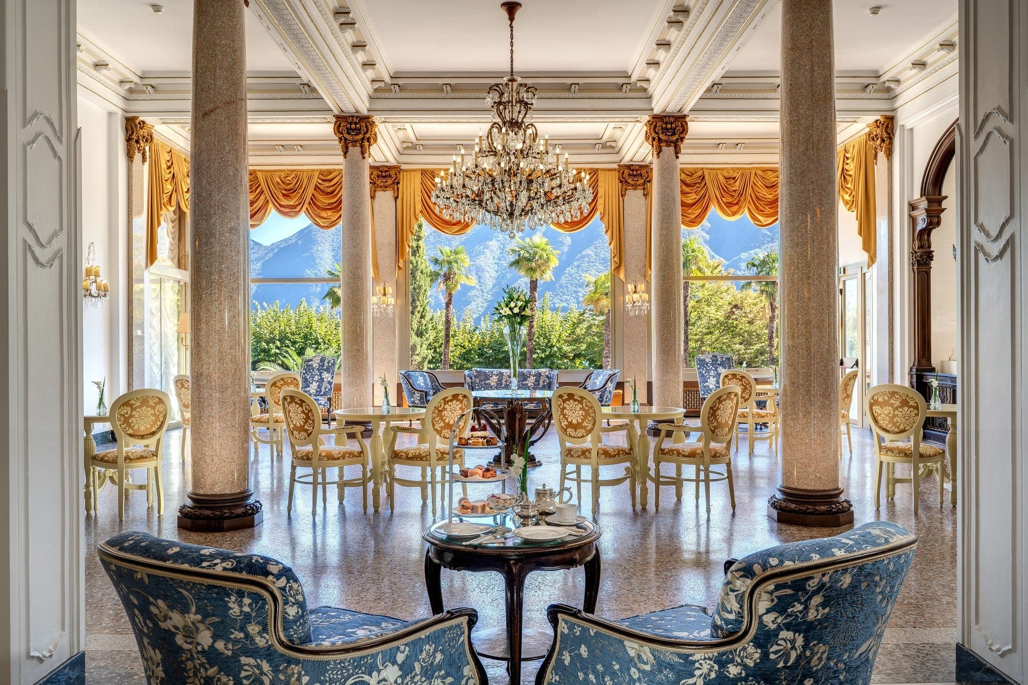 Hall principale dell’Hotel Splendide Royal a Lugano con lampadario, colonne di marmo e vetrate aperte sul giardino.
