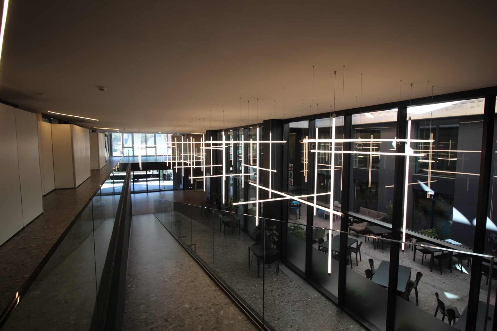 Galerie in den Büroräumen der Multimmobiliare SA mit Glasbrüstung und Lichtinstallation über dem Atrium.