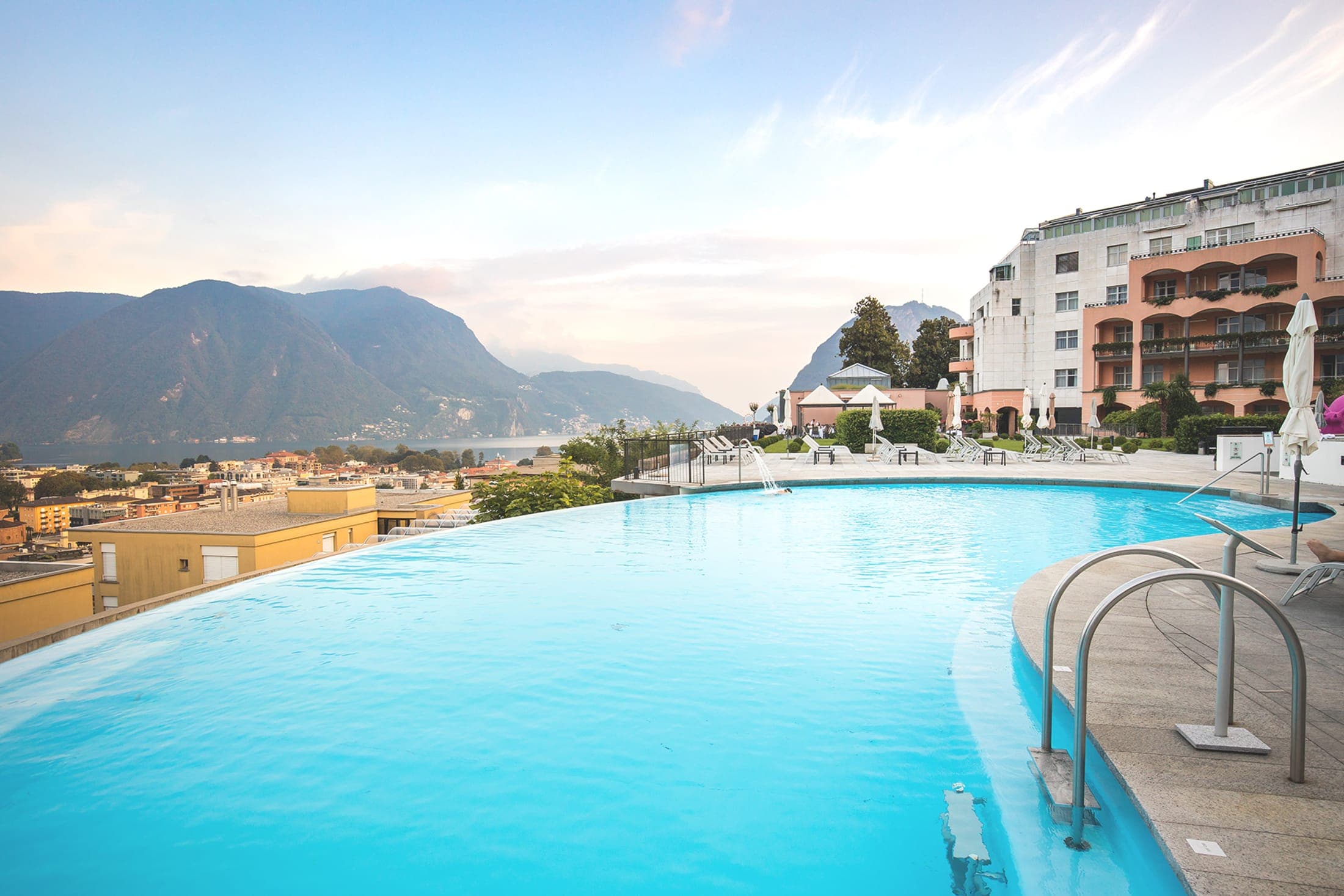 Piscina panoramica di Villa Sassa sopra Lugano con la città e le montagne sullo sfondo.