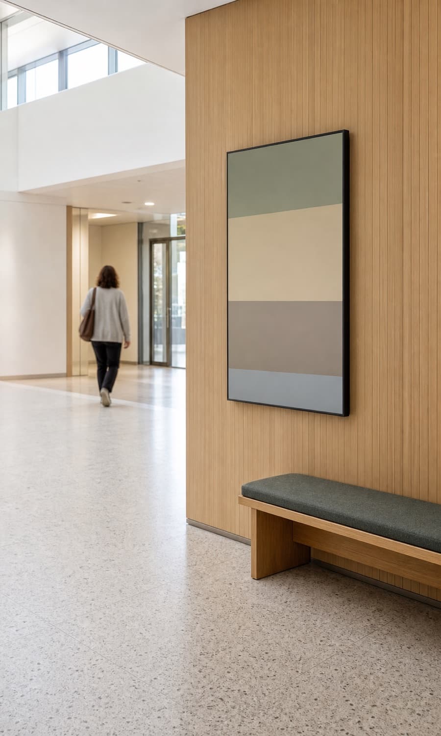 Ingresso d’ospedale luminoso con display di orientamento, parete in legno e panca.
